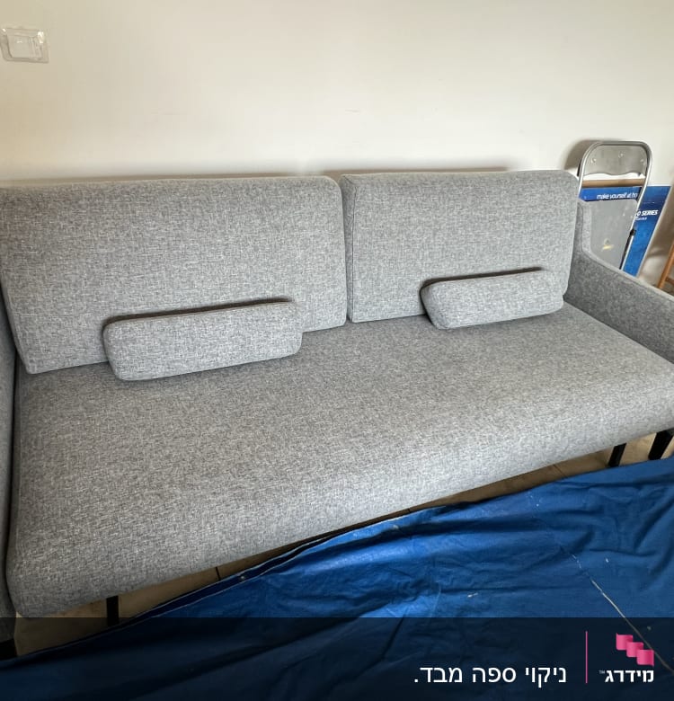 ספה אפורה עם כיסוי כחול על הרצפה